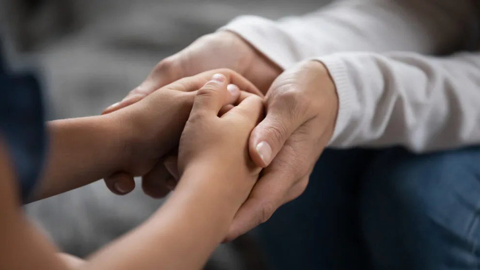 Close up caring mother touching adorable little daughter hands